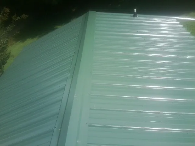 New green metal panels meeting at the ridge of a roof — Flat Roof Repair work by our crew in Sugar Tree