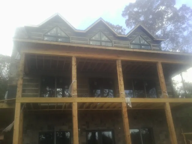 Dormers and porch framing on a large log home under construction — Roof Coating work by our crew in Sugar Tree