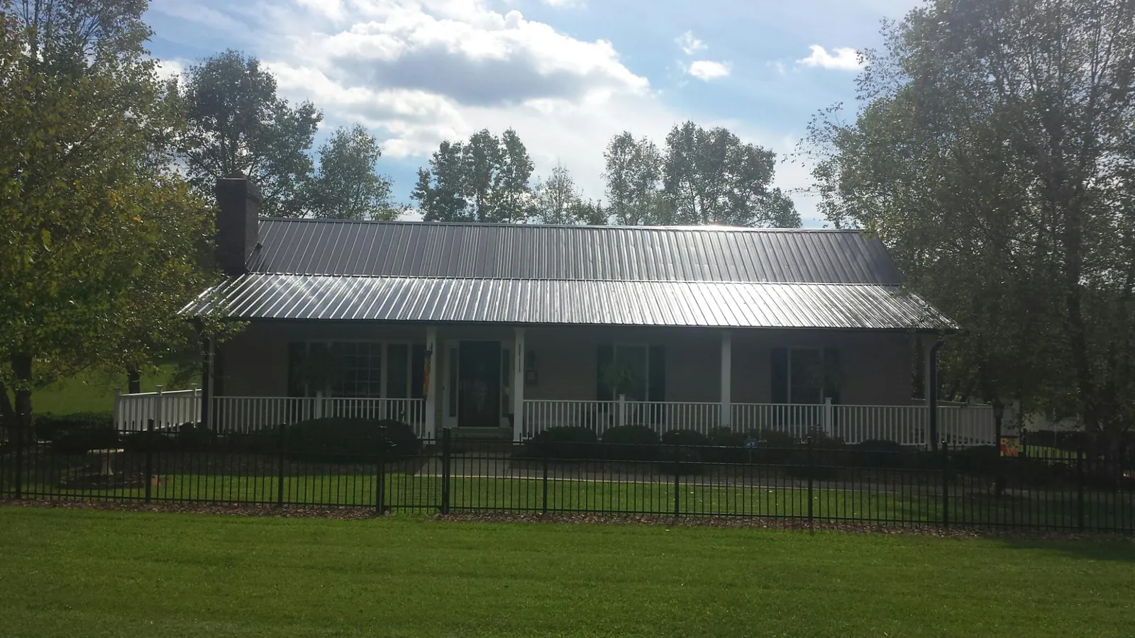Gray metal roof on a brick ranch with a full width front porch — Gutter Guard Installation work by our crew in Sugar Tree