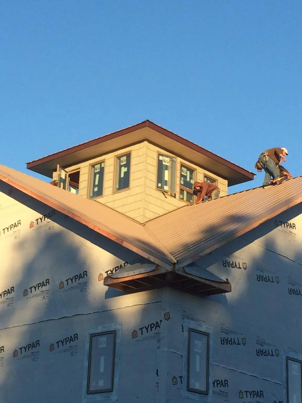 Roofers working around a rooftop cupola on a new metal roof at sunset — Roof Waterproofing in Sugar Tree by Roofing Brothers